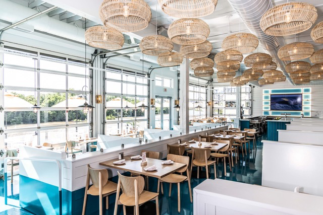 Instagrammable Seafood Restaurant Interior in Rocketts Landing Richmond, VA. The interior includes beautiful wicker lighting, table and booth seating and an open-air door facing the James River and patio dining.